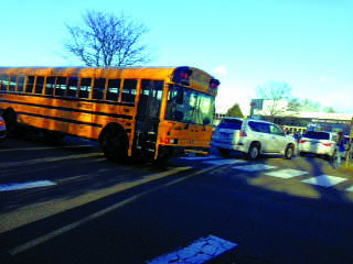 Buses have to negotiate a daily long line of cars picking  up and dropping off their children.