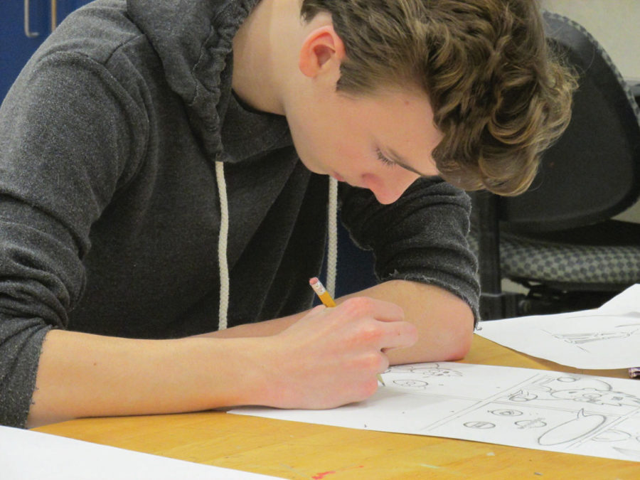An 8th grade student sketches his comic design.