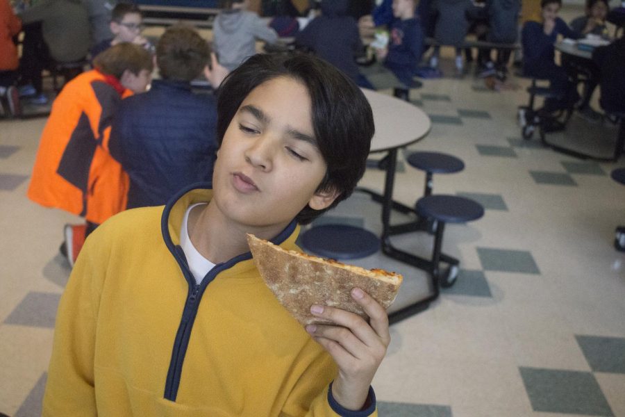 A 7th grade enjoying a slice of pepperoni pizza in the cafeteria.